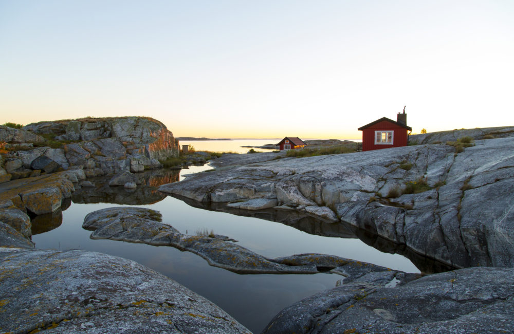 Soluppgång över skärgårdskobbe med små stugor