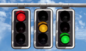 Three traffic lights against blue sky background